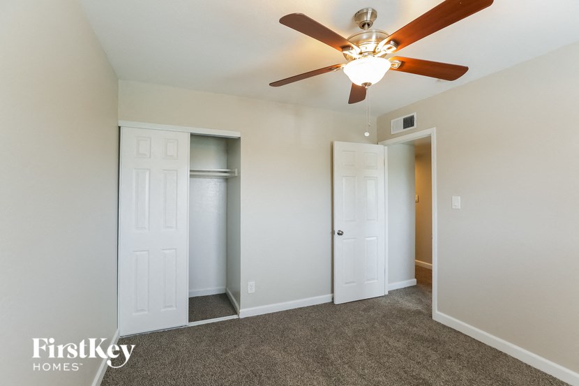 a bedroom with a ceiling fan and a closet