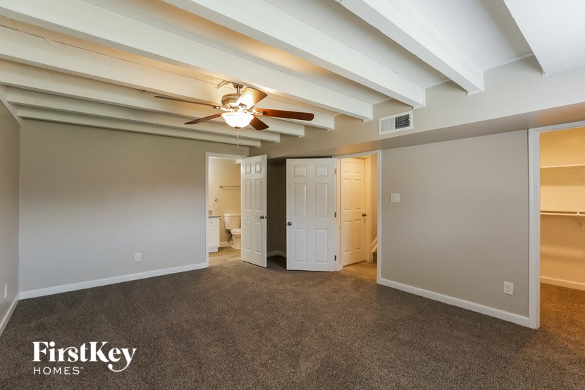 a living room with a ceiling fan and a door to a bathroom