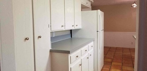 A kitchen with white cabinets and a white refrigerator.