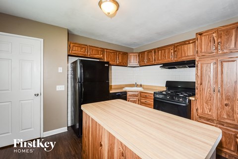 A kitchen with wooden cabinets and a black fridge.