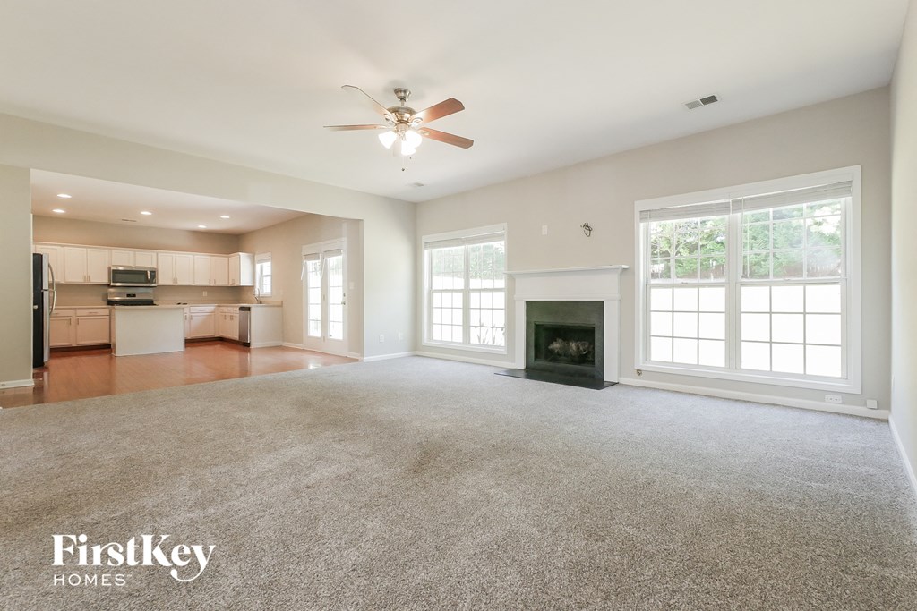 A spacious living room with a fireplace and a ceiling fan.