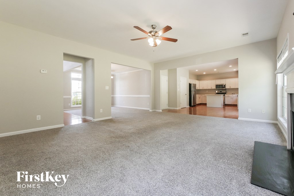 A spacious living room with a ceiling fan and a black rug on the floor.