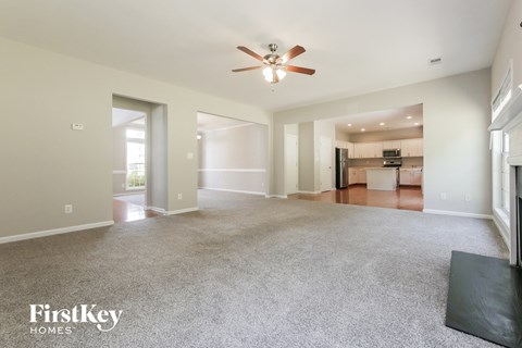 A spacious living room with a ceiling fan and a black rug on the floor.