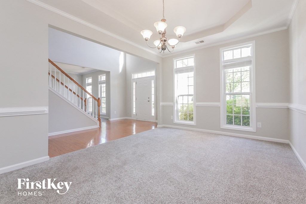 A spacious room with a carpeted floor and a chandelier hanging from the ceiling.