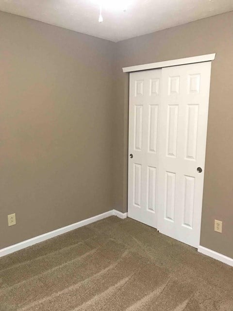 a bedroom with a white door and a carpeted floor