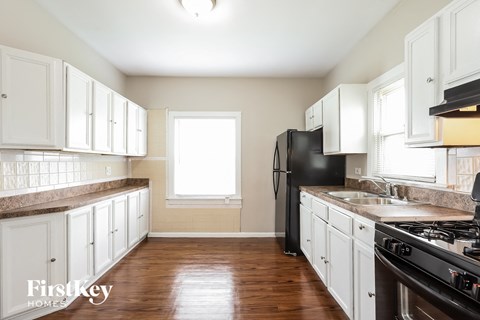 A kitchen with white cabinets and a black fridge.