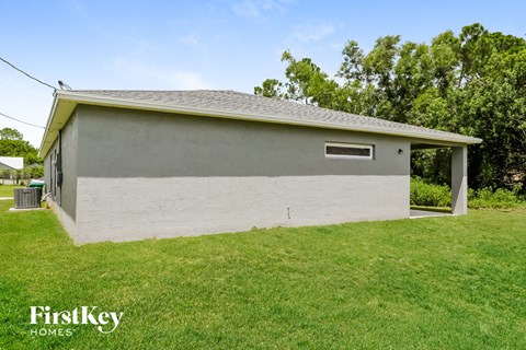 the backyard of a white brick house with grass and trees