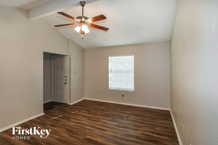 an empty living room with a ceiling fan and a door to a closet