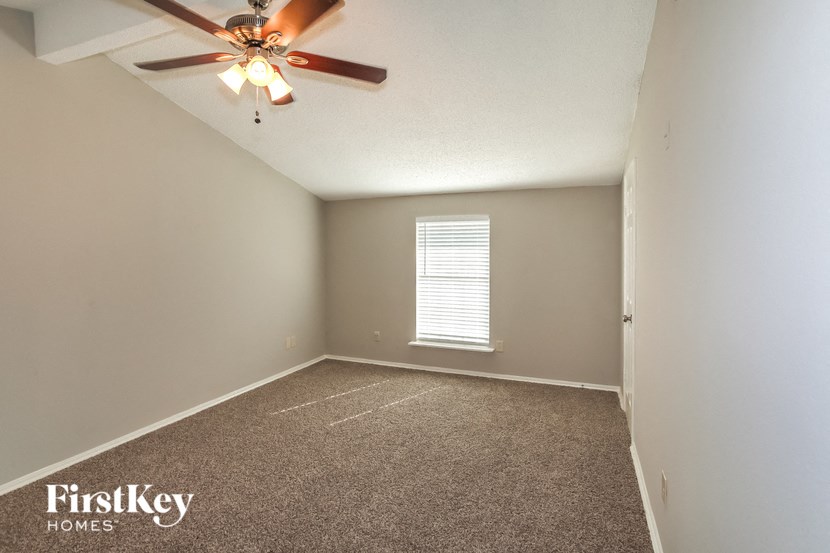 an empty room with a ceiling fan and a window