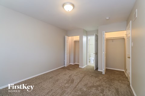 a master bedroom with a carpeted floor and a door to a bathroom