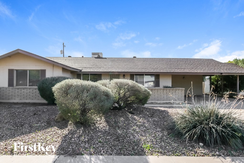 A house with a gravel driveway and a bush in front.