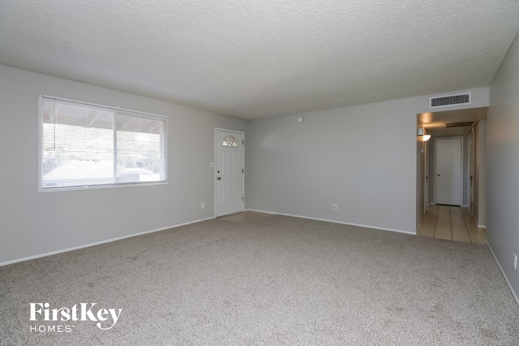 A spacious room with a carpeted floor and a door leading to another room.