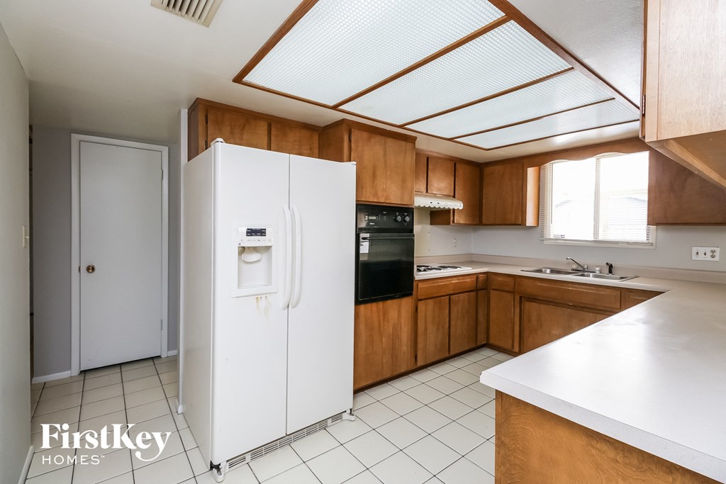 A kitchen with a white fridge and wooden cabinets.