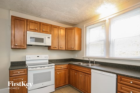A kitchen with wooden cabinets and a white stove top oven.