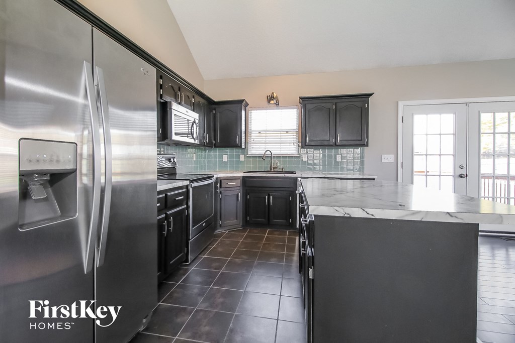 a large kitchen with black cabinets and stainless steel appliances