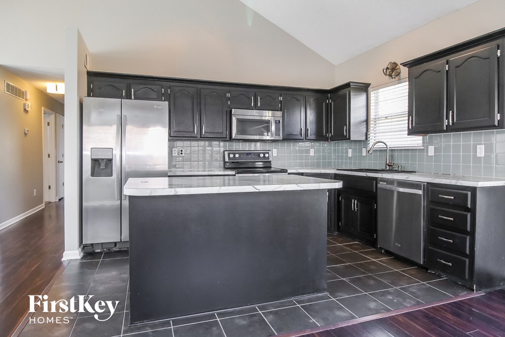 a black and white kitchen with stainless steel appliances and black cabinets