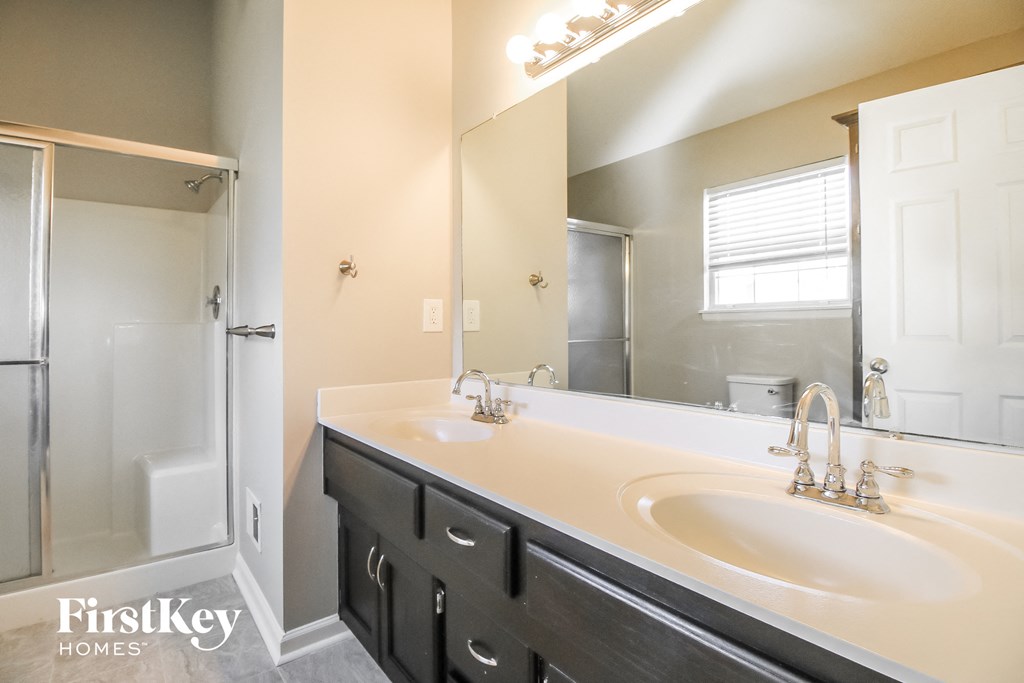 a bathroom with two sinks and a shower and a large mirror