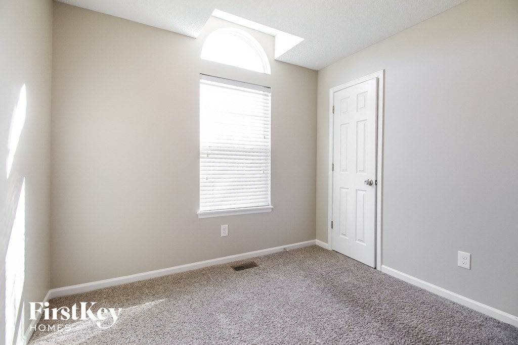 a bedroom with a white door and a window and a carpeted floor