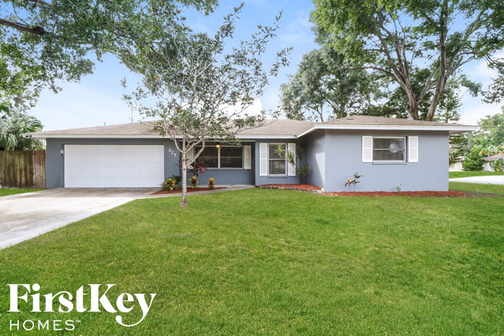 A house with a grey roof and a white garage door is for sale.