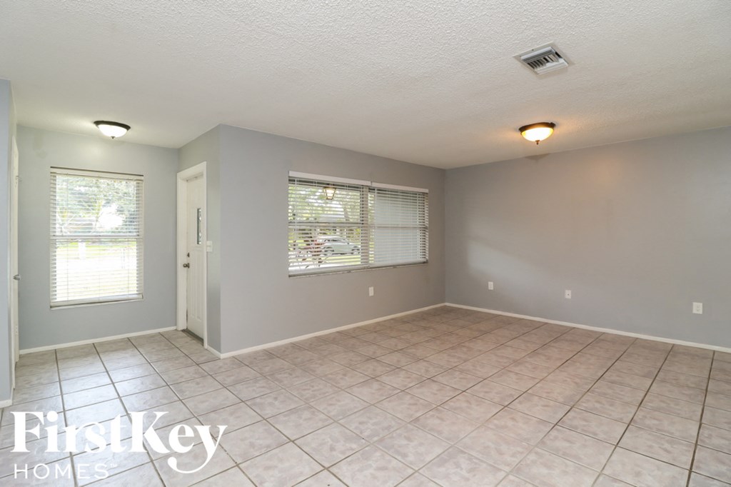 A room with a tiled floor and a window with blinds.