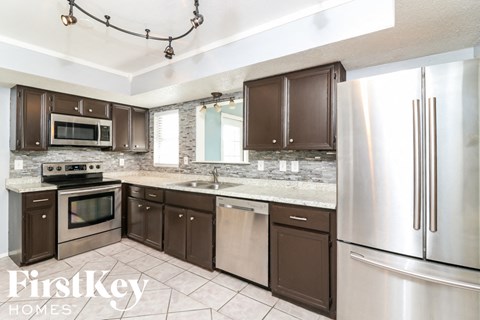 A kitchen with brown cabinets and a stainless steel refrigerator.
