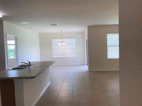 A kitchen with a sink and a window with blinds.