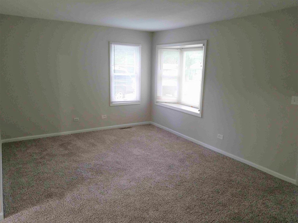 a room with carpet and two windows