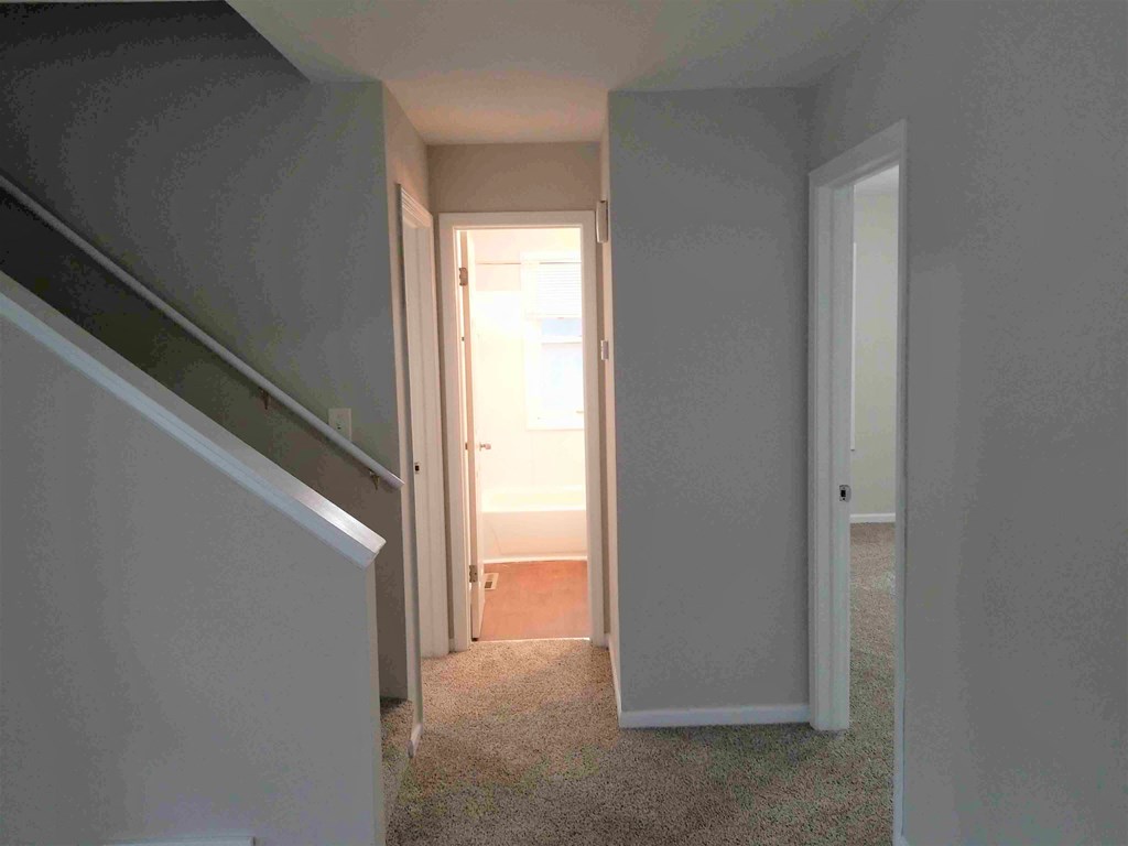 a view from the bottom of the stairs looking into the hallway with the door open