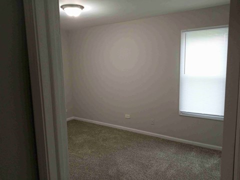 a bedroom with a window and a carpeted floor