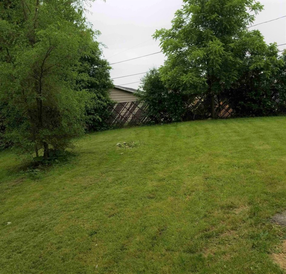 a yard with green grass and a house in the background