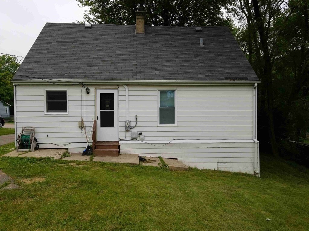 a small white house with a porch and a lawn