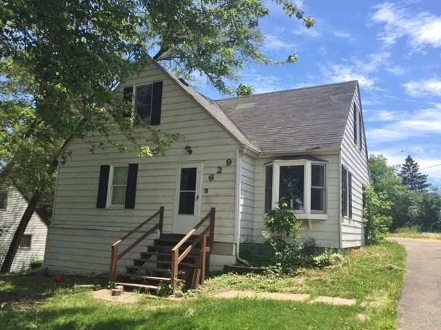 a white house with a wooden deck and a tree