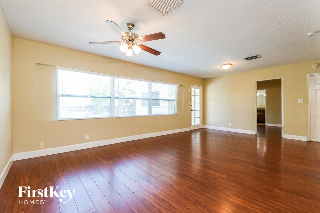 A spacious room with a ceiling fan and wooden flooring.