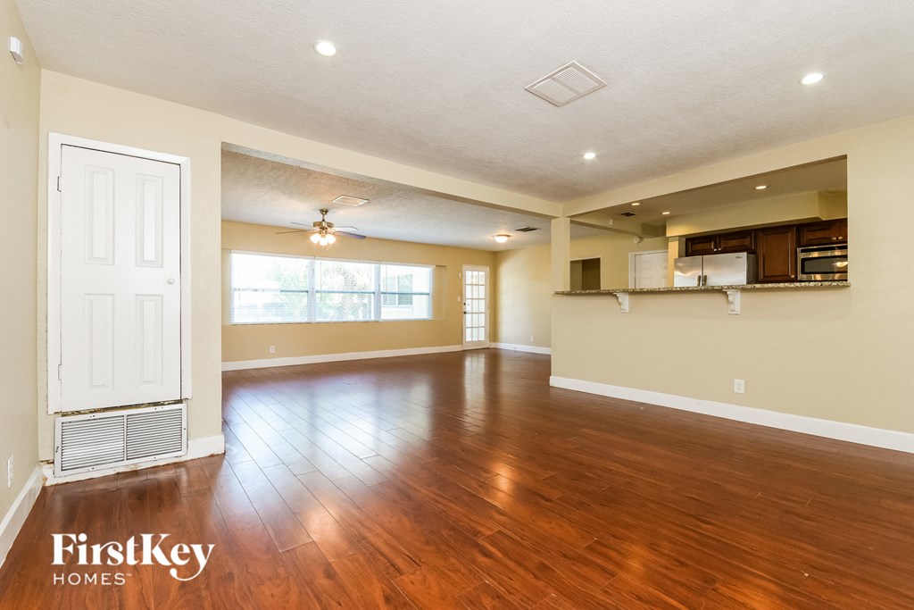 A spacious room with wooden floors and a ceiling fan.