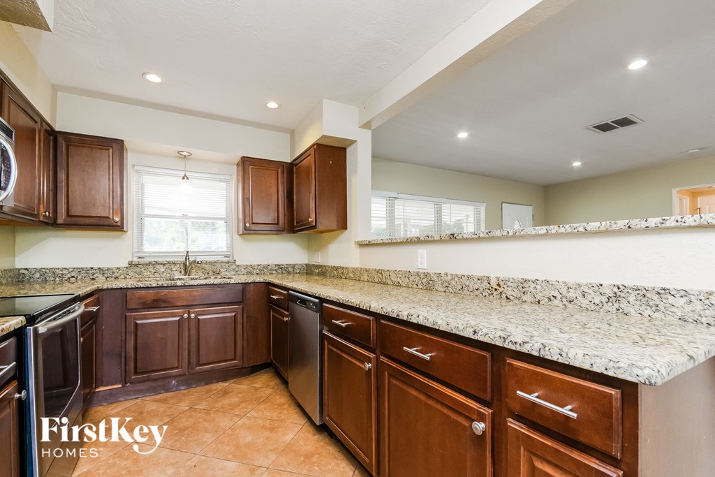 A kitchen with brown cabinets and a granite countertop.