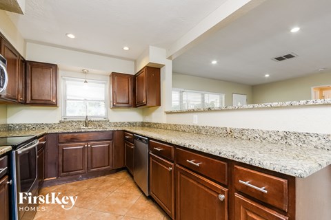 A kitchen with brown cabinets and a granite countertop.