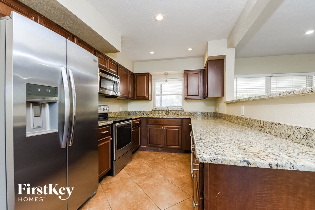 A kitchen with a stainless steel refrigerator and brown cabinets.