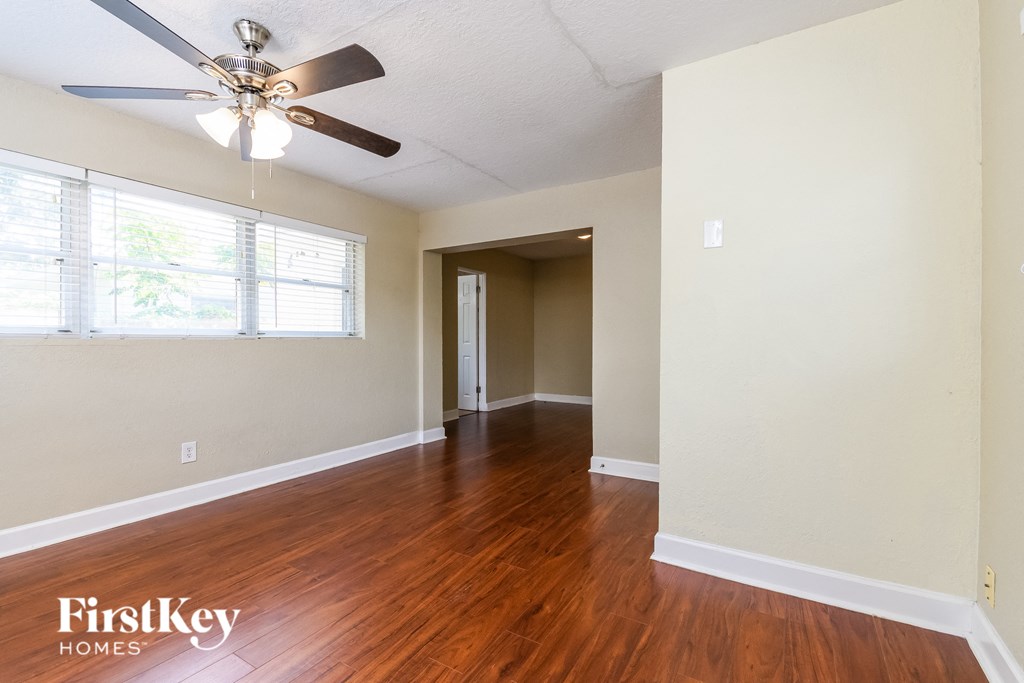 A room with a fan and wooden floors.