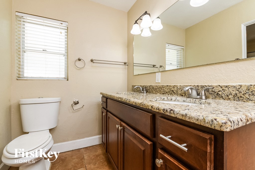 A bathroom with a toilet, sink, and mirror.