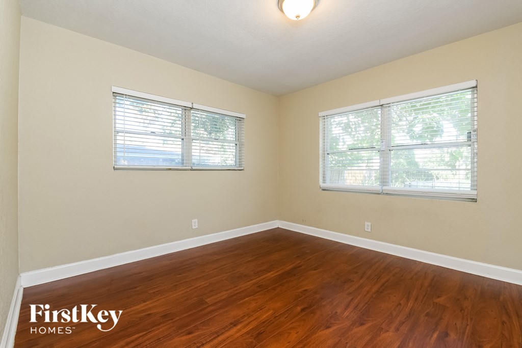 A room with wooden floors and two windows.