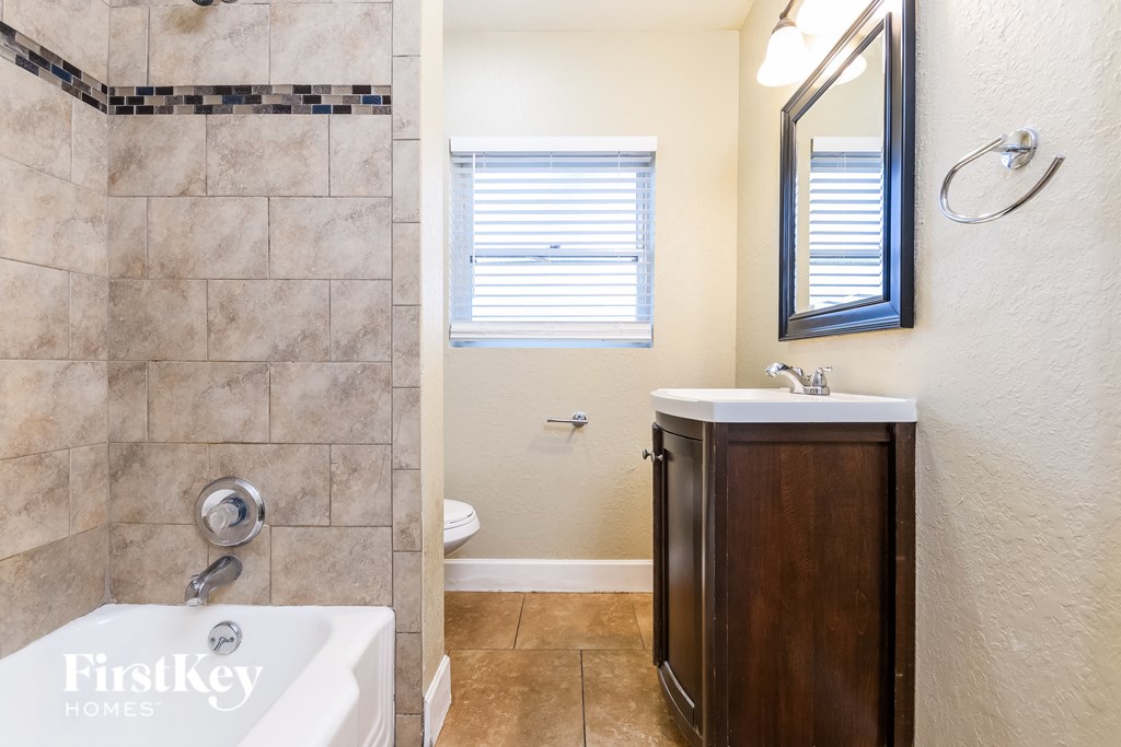 A bathroom with a white tub and a wooden cabinet.