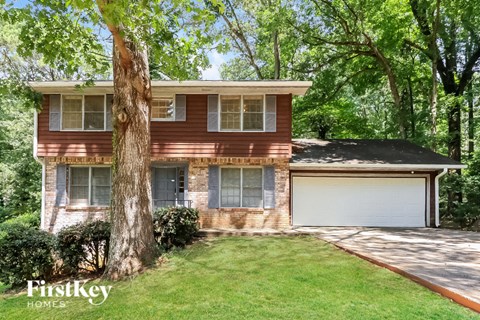 a brick house with a garage and a tree in the yard