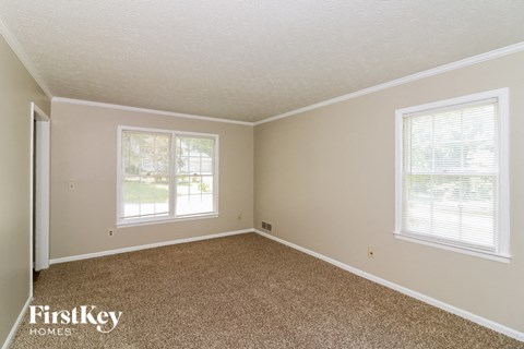 the bedroom of a house with carpet and two windows
