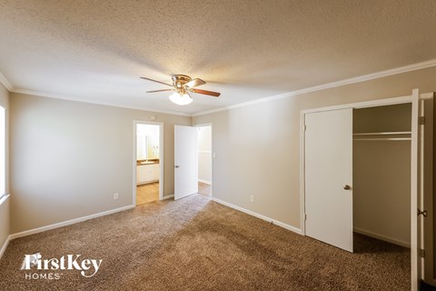 a master bedroom with carpet and a ceiling fan