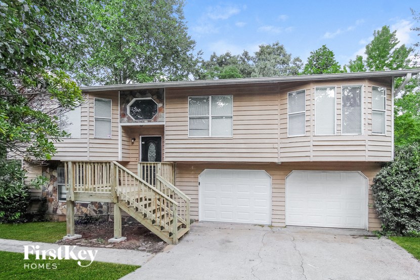 a tan house with two garage doors and a staircase