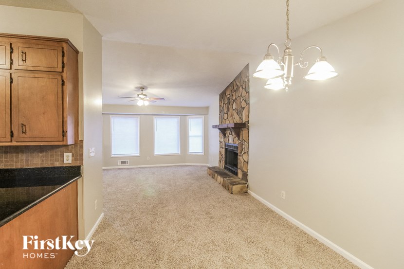 an empty living room with a fireplace and a kitchen