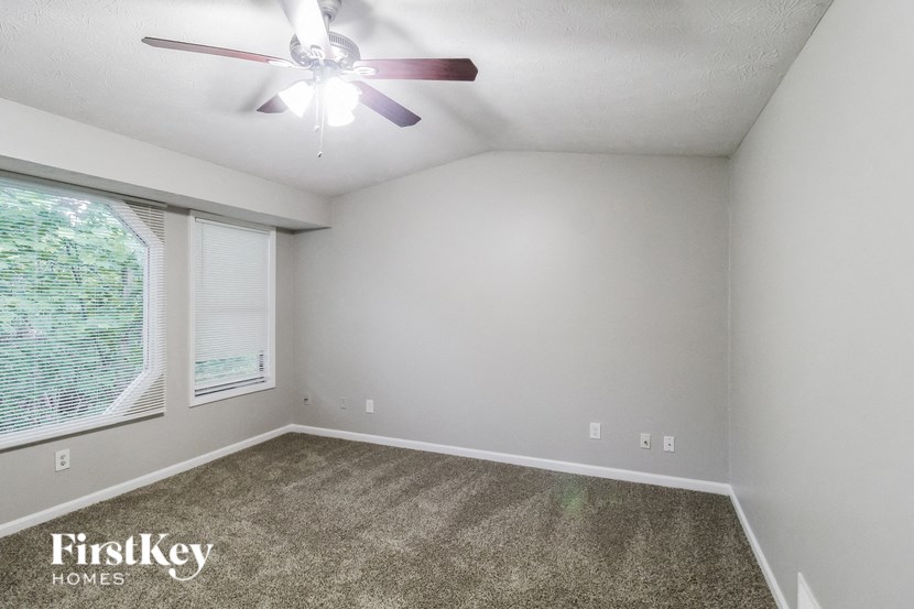 a bedroom with a ceiling fan and a large window