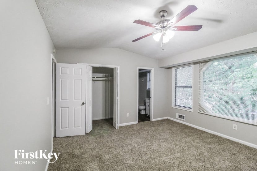 an empty living room with a ceiling fan and a large window