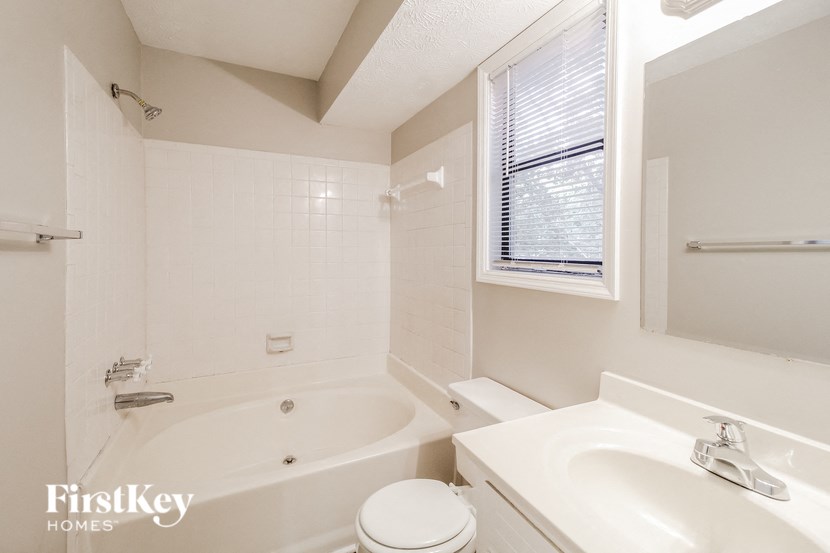 a white bathroom with a tub and a sink and a toilet