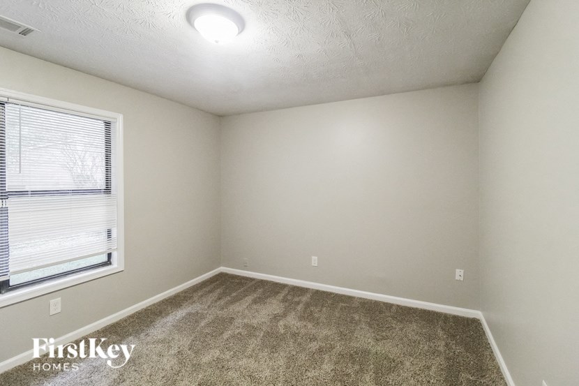 a bedroom with a large window and a carpeted floor
